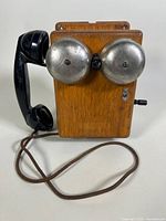 Front view of antique Western Electric Type 315G telephone showing oak wooden box, twin metal ringer bells, black handset, and cloth cord.
