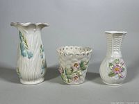Front view of three porcelain vases showing floral designs and textures.