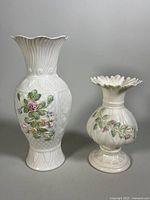 Front and side views of two cream Belleek vases with hand-painted raised floral patterns in pastel colors.