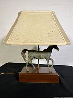Full view of lamp with stained fabric shade, bronze horse figure on wood base.