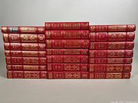 21 red leather bound books arranged in three rows showing uniform gilt spines