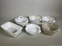 Front view of five CorningWare baking dishes, four with glass lids and one loaf pan, showing blue cornflower and floral patterns.