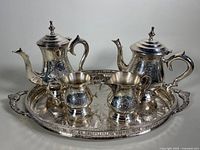 Tea and coffee service on tray showing all main items with ornate engraved silver plating.