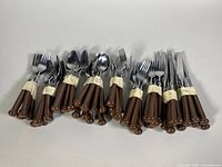 Complete set of Oxford Hall cutlery arranged in groups, tied with tape, showing forks, knives, tablespoons, and teaspoons with brown plastic handles and stainless steel heads.