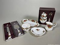 Set of Royal Albert Old Country Roses china including cake cutter and pie server in original packaging, trinket dish, sugar bowl, creamer, and petit fours dish shown together