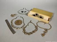 Full lot layout showing assorted costume jewelry including Sarah Coventry sunflower set in box and various necklaces, brooches, bracelets, earrings