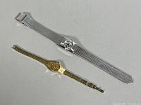 Two women's wristwatches displayed on a flat surface, one gold-tone Seiko and one silver-tone Pagol