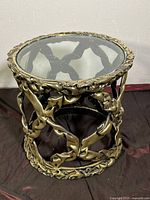 Side view of the cylindrical side table showing the detailed vine-like painted fiberglass base and floating clear glass top.