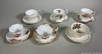 Overview of six different porcelain teacup and saucer sets showing a variety of floral and gold trim designs.