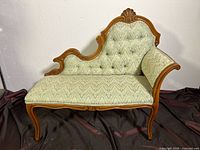Front view of a vintage lounge chair showing the ornate wooden frame and patterned fabric upholstery with tufted backrest