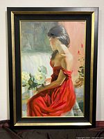 Full framed artwork showing seated woman in red dress holding white roses, signed by Volegov.