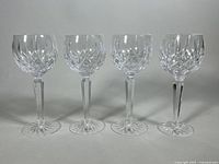 Front view of four Waterford Lismore hock wine glasses aligned side by side showing their diamond cut pattern, faceted stems, and starburst base details.