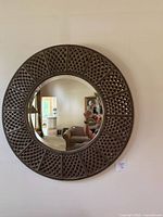 Front view of round mirror showing bronze lattice metal frame and reflective glass