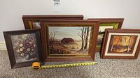 Four framed artworks displayed on floor with measuring tape showing size approximately 12 inches wide each