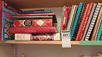Top shelf with stacked cookbooks, a puzzle book, and binders mostly horizontal