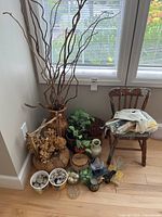 Photo showing overall assortment including a small wood chair, dried floral arrangements, vases, potted artificial plants, candles, and containers with decorative stones.