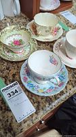 Overview of four fine china teacups and saucers with different floral patterns and gold trim