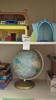 Two shelf display with a plastic dollhouse, globe on stand, and assorted game boxes.