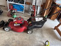 Left side profile view of the Craftsman red self-propelled rotary lawn mower with grass collection bag and handlebar visible.