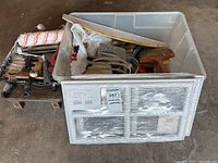 Overview of plastic bin and adjacent paint tools including rollers and scrapers beside a window frame