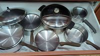 Two drawers of assorted pots, pans, and bakeware including frying pans, saucepans, glass lid cookware, bundt pan, glass baking dish, and specialty cooking items