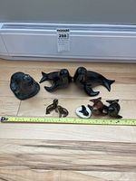 Top view showing the entire assortment of soapstone and ceramic seal figurines placed on a wooden floor with a measuring tape for scale.