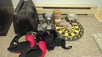 Full view of sporting goods including boxing gloves, dumbbells, dartboard, bowling balls with bag, and bocce ball set.