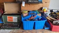 Overall view of a workbench with various tools and hardware including containers and socket sets