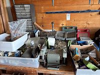 Wide view of workbench showing Sears 5 inch bench grinder surrounded by various tools, screws, drill bits, and containers.