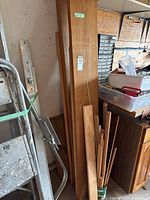 Multiple pieces of wood leaning in corner, including tall and narrow parts with used condition.