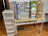 Overall view of plastic drawer units on table alongside boxed organizers and vacuum bag kits
