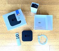 All components laid out: Apple TV unit, Siri Remote, Lightning cable, power cord, guide, box