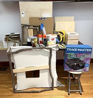 Overall view of projector, frames, panels, paints and craft items on table