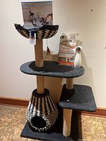 Front view of cat tree with boxed drinking fountain, packaged heated mat, and laser toy placed on perch