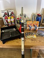 Group overview with cleaning kit pole, paint tray, Fire Gone cans, lighters, WD-40, chains and other bundled items on workbench