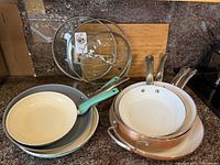 Stacked pans and three glass lids displayed on countertop