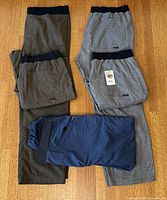 Five pairs of Prana pants laid out: four grey/olive Vaha Balance, one blue Moaby