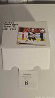 Top view of the white box containing the hockey cards with a sample card displayed on top showing a player in action during the game and label mentioning 2022-23 Upper Deck Series 2 with card numbers 351-450.