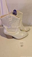 Side view of shiny white women's ankle boot showing rhinestone details, mid-height wooden heel and brand new with tags.