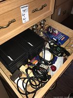 Drawer containing two Bose Model 25 surface mount speakers, cables, computer mouse, and brass candle holders.