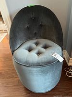 Front view of upholstered tufted chair showing round seat and backrest with button tufting