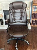 Full front view of brown electronic office chair showing padded backrest, seat, armrests, and five caster wheels. Chair seat and armrest covers show wear and wrinkles.