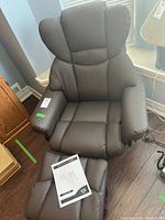 Front view of recliner chair with manual on seat and footstool partly visible