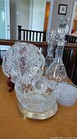 Photo showing two crystal decanters, a large cut glass serving bowl, and a plate holder with intricate star and floral designs on wood stand