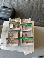 Five boxed Defiant Naples satin nickel door knob sets placed on a storage container.