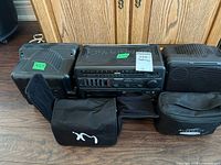 Front view of the stereo system and accessories showing stereo, speakers, and carrying cases on floor.