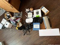 Overview of lot showing VR Shinecon headset, multiple electronic devices, cables, Canon cartridge box, and accessories spread on wooden floor