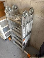 Folded aluminum ladder leaned against garage wall