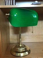 Front view of desk lamp showing green glass shade and brass base