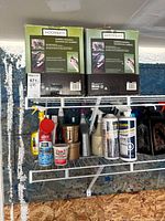 Two boxed Moonrays landscape lighting sets on a metal shelf with other household cleaning items beneath.